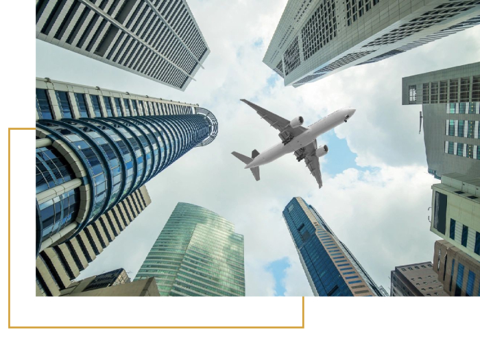 A plane flying over some skyscrapers in the sky.